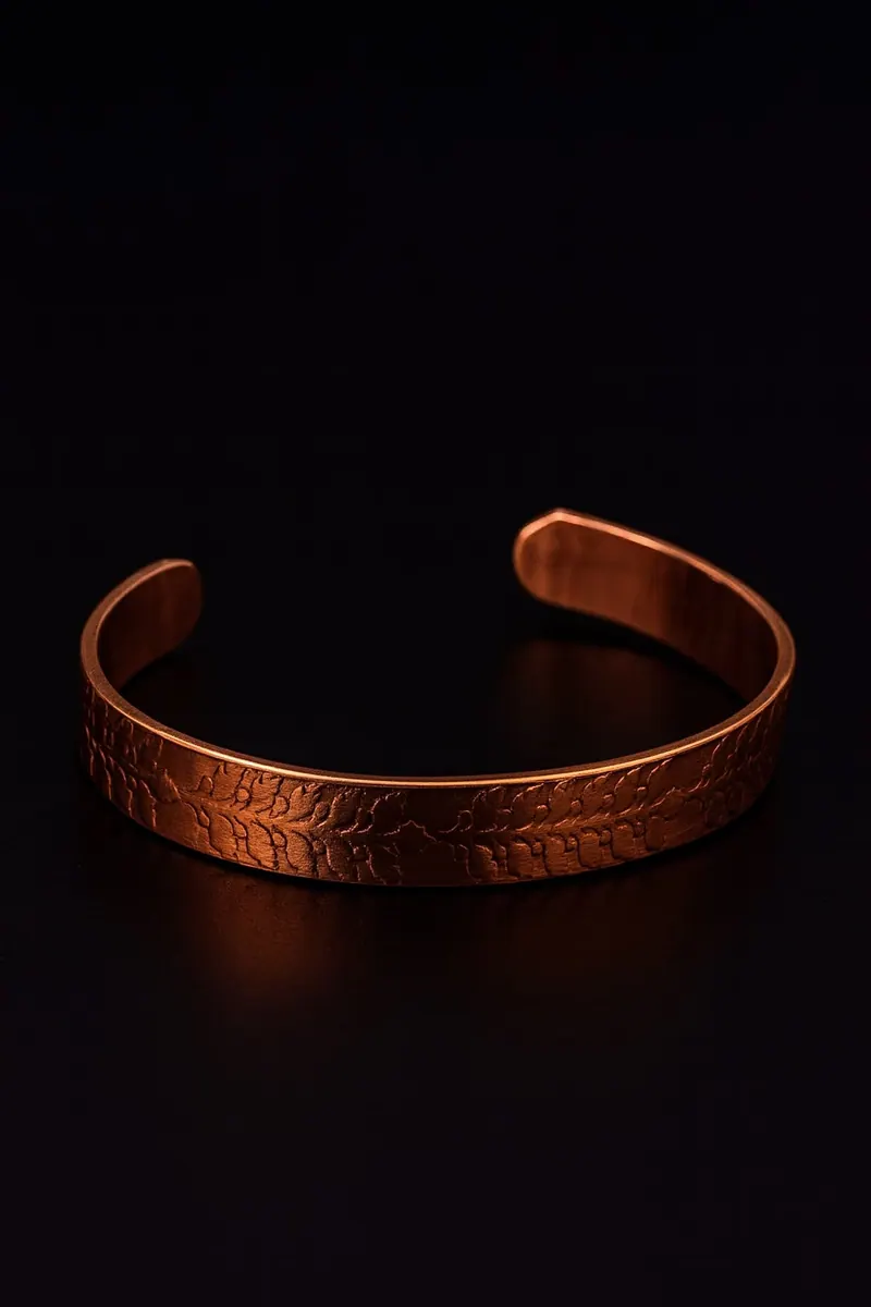 Pulseira de cobre com folhas em relevo, sobre fundo preto