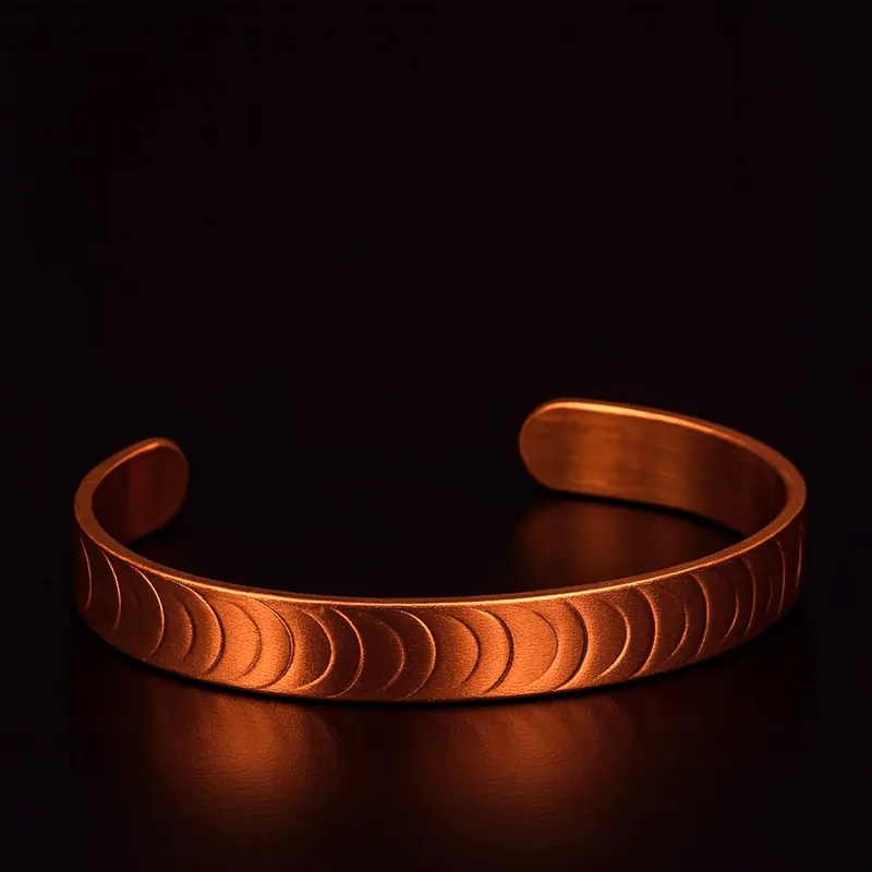 Pulseira de cobre com meias-luas em relevo, sobre fundo escuro